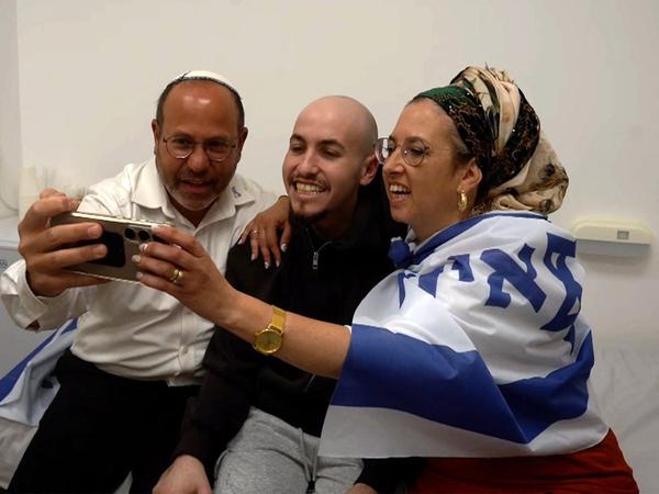 This handout picture released by the Israeli army shows released Israeli hostage Eitan Mor (C), one of the former captives in Gaza since the 2023 October 7 attacks by Palestinian militants, posing for a "selfie picture" with his family after being handed over in a prisoner-hostage swap and a ceasefire deal between Israel and Hamas in Israel on October 13, 2025. (Photo by Israeli Army / AFP) / === RESTRICTED TO EDITORIAL USE - MANDATORY CREDIT "AFP PHOTO / Handout / Israeli Army' - NO MARKETING NO ADVERTISING CAMPAIGNS - DISTRIBUTED AS A SERVICE TO CLIENTS ==