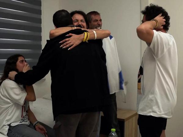 This handout picture released by the Israeli army shows released Israeli hostage Guy Gilboa-Dalal (in black garment), one of the former captives in Gaza since the 2023 October 7 attacks by Palestinian militants, being embraced by a family member after being handed over in a prisoner-hostage swap and a ceasefire deal between Israel and Hamas in Israel on October 13, 2025. (Photo by Israeli Army / AFP) / === RESTRICTED TO EDITORIAL USE - MANDATORY CREDIT "AFP PHOTO / Handout / Israeli Army' - NO MARKETING NO ADVERTISING CAMPAIGNS - DISTRIBUTED AS A SERVICE TO CLIENTS ==