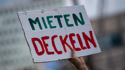 Bei einer Demonstration gegen hohe Mieten in Berlin hält ein Teilnehmer ein Plakat mit der Aufschrift „„Mieten Deckeln“ in die Luft.