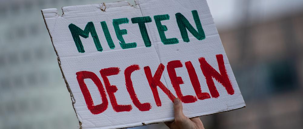 Bei einer Demonstration gegen hohe Mieten in Berlin hält ein Teilnehmer ein Plakat mit der Aufschrift „„Mieten Deckeln“ in die Luft.