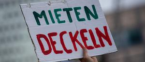 Bei einer Demonstration gegen hohe Mieten in Berlin hält ein Teilnehmer ein Plakat mit der Aufschrift „„Mieten Deckeln“ in die Luft.