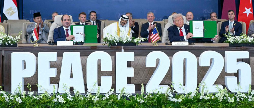 US President Donald Trump (R) and Egypt's President Abdel Fattah al-Sisi show signed documents during a summit on Gaza in Sharm el-Sheikh on October 13, 2025. Trump on October 13 hailed a Gaza summit in Egypt as a "tremendous day" for the Middle East, saying a document would be signed on "rules and regulations" for future talks. (Photo by SAUL LOEB / AFP)