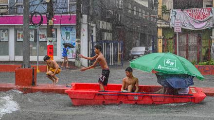 Nach starkem Regenfall spielen Kinder mit einem verlassenen Rettungsboot in Quezon City, ein der eingemeindeten Metropolen von Manila, der Hauptstadt der Philippinen.