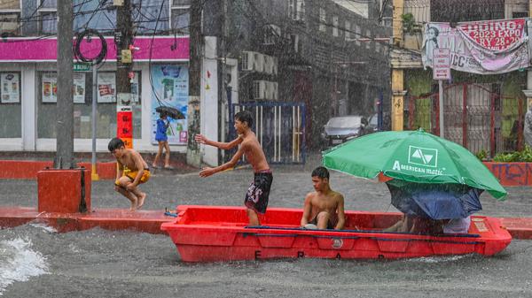 Nach starkem Regenfall spielen Kinder mit einem verlassenen Rettungsboot in Quezon City, ein der eingemeindeten Metropolen von Manila, der Hauptstadt der Philippinen.