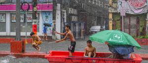 Nach starkem Regenfall spielen Kinder mit einem verlassenen Rettungsboot in Quezon City, ein der eingemeindeten Metropolen von Manila, der Hauptstadt der Philippinen.