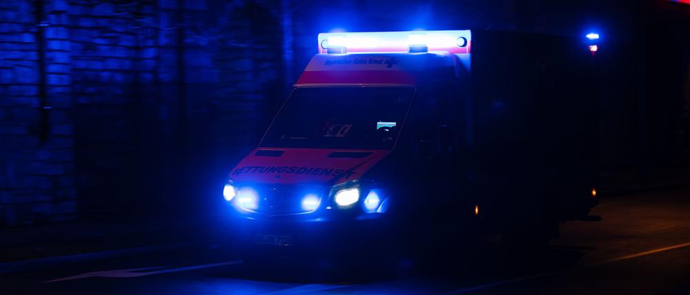 Ein Krankenwagen fährt nachts mit Blaulicht durch eine Straße. (Symbolbild)