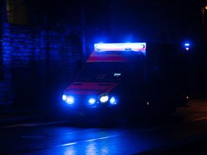 Ein Krankenwagen fährt nachts mit Blaulicht durch eine Straße. (Symbolbild)