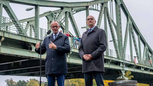 14.10.2025, Brandenburg, Potsdam: Bundeskanzler Friedrich Merz (l, CDU) steht neben Dietmar Woidke (SPD), Ministerpräsident von Brandenburg, neben der Glienicker Brücke beim Pressestatement nach seinem Antrittsbesuch in Brandenburg. Foto: Michael Kappeler/dpa +++ dpa-Bildfunk +++
