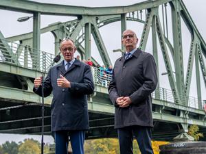 14.10.2025, Brandenburg, Potsdam: Bundeskanzler Friedrich Merz (l, CDU) steht neben Dietmar Woidke (SPD), Ministerpräsident von Brandenburg, neben der Glienicker Brücke beim Pressestatement nach seinem Antrittsbesuch in Brandenburg. Foto: Michael Kappeler/dpa +++ dpa-Bildfunk +++