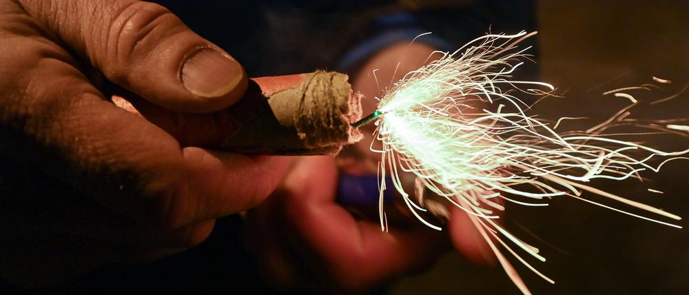 Ein Mann zündet einen Böller am Silvesterabend an.