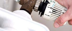 Eine Frau dreht am Thermostat einer Heizung (Symbolbild).