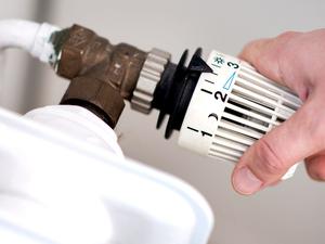 Eine Frau dreht am Thermostat einer Heizung (Symbolbild).