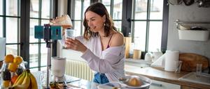 Eine junge Frau bereitet Essen vor einer Kamera zu.