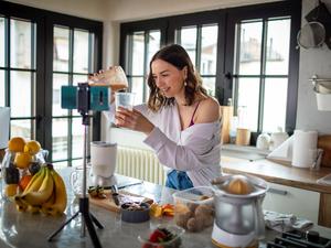 Eine junge Frau bereitet Essen vor einer Kamera zu.