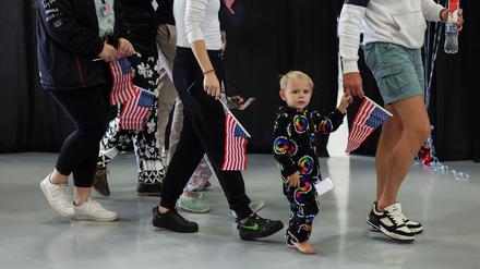 Some of the first group of white South Africans granted refugee status for being deemed victims of racial discrimination under U.S. President Trump's Refugee plan, hold U.S. flags as they walk at Dulles International Airport, in Dulles, Virginia, U.S., May 12, 2025. REUTERS/Kevin Lamarque