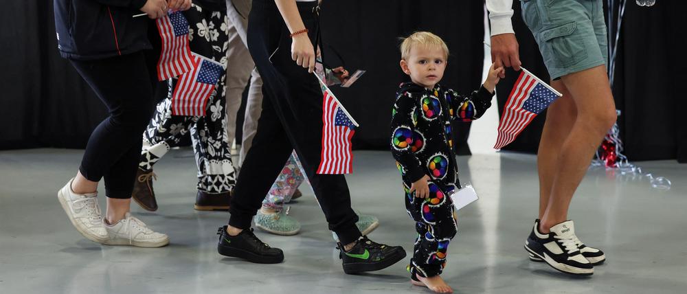 Some of the first group of white South Africans granted refugee status for being deemed victims of racial discrimination under U.S. President Trump's Refugee plan, hold U.S. flags as they walk at Dulles International Airport, in Dulles, Virginia, U.S., May 12, 2025. REUTERS/Kevin Lamarque