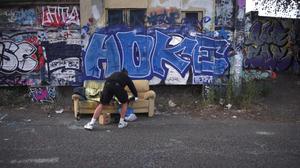 Filmstill aus Simone Zauggs Video „Home Less“: In der Rolle eines Obdachlosen lässt sich die Künstlerin von einem Graffiti-Künstler mit dem Schriftzug „Home Less“ übersprühen.