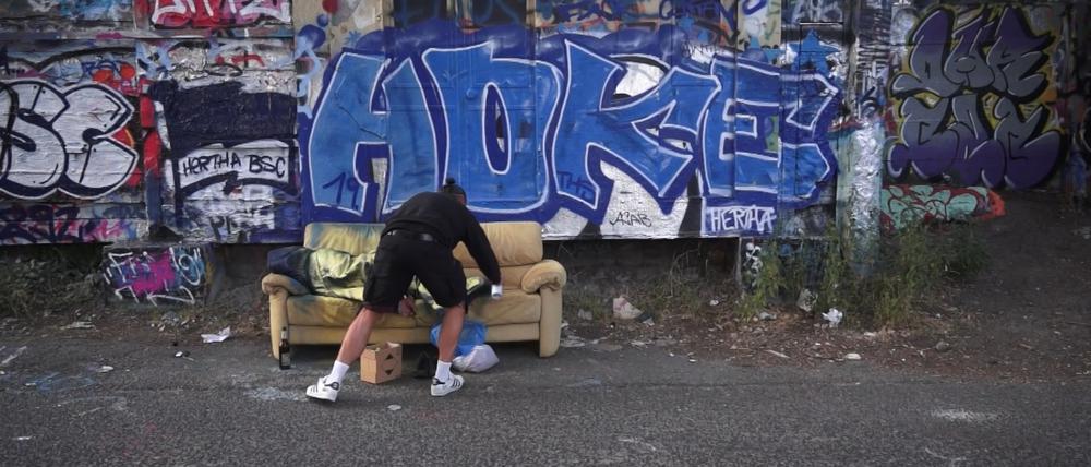 Filmstill aus Simone Zauggs Video „Home Less“: In der Rolle eines Obdachlosen lässt sich die Künstlerin von einem Graffiti-Künstler mit dem Schriftzug „Home Less“ übersprühen.