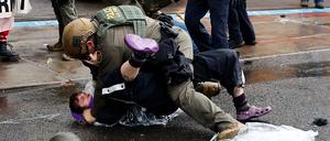 Ein Bundesbeamter geht gegen einen Demonstranten vor. 