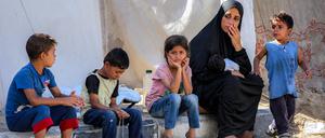 Eine Frau sitzt mit Kindern vor Zelten in einem Lager für Kriegsflüchtlinge im nördlichen Nuseirat im zentralen Gazastreifen.