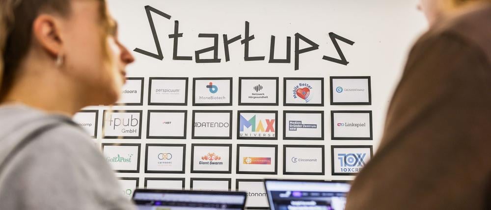 Junge Leute vor einer Tafel mit Start-up-Firmen