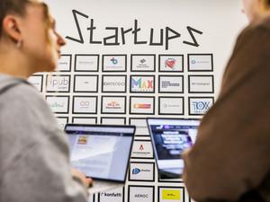 Junge Leute vor einer Tafel mit Start-up-Firmen