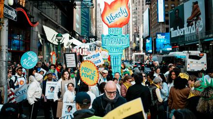 Demonstranten schieben bei den No Kings-Protesten eine Pappfackel die 7th Avenue in Manhattan entlang.