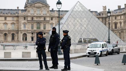 Polizisten stehen neben der berühmten Pyramide vor dem Louvre.