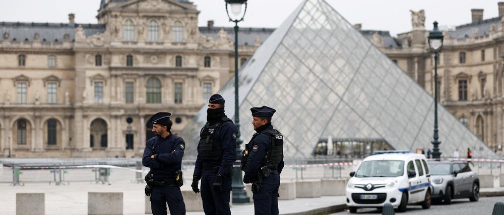 Polizisten stehen neben der berühmten Pyramide vor dem Louvre.