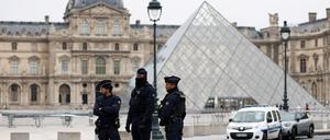 Polizisten stehen neben der berühmten Pyramide vor dem Louvre.