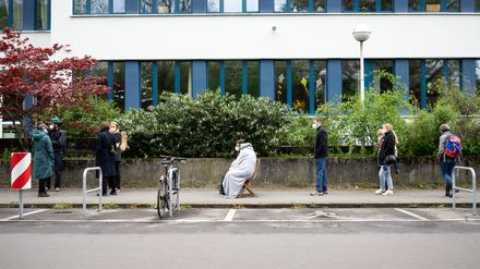 14.05.2021, Berlin: Maikel Fritz und Mia Faustmann (M) aus Neukölln warten auf Klappstühlen sitzend auf dem Gehweg vor einer Turnhalle einer Schule in Neukölln, wo eine Schwerpunktimpfung gegen Corona stattfindet. Bei dem gemeinsamen Pilotprojekt des Senats und des Bezirksamts Neukölln sind Anwohner festgelegter Straßen in einem Viertel mit hoher Inzidenz eingeladen, eine Corona-Impfung ohne Termin zu erhalten. Geimpft wird mit den Impfstoffen der Firmen Johnson & Johnson sowie Moderna. Foto: Bernd von Jutrczenka/dpa +++ dpa-Bildfunk +++