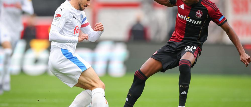 Kiel-Kapitän Steven Skrzybski (links) und Pape Demba Diop von Nürnberg kämpfen um den Ball.