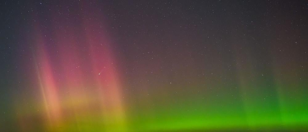 Polarlicht und Komet leuchten am Nachthimmel.