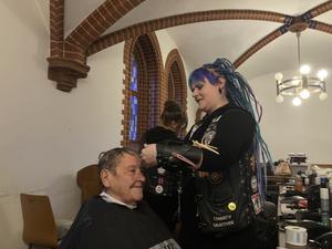  "Barber Angel" Anni schneidet einem Gast kostenlos die Haare in der Pauluskirche.