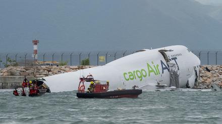 Rettungskräfte auf Booten schwimmen um das Frachtflugzeug, das auf dem Flughafen in Hongkong von der Landebahn abgekommen ist.