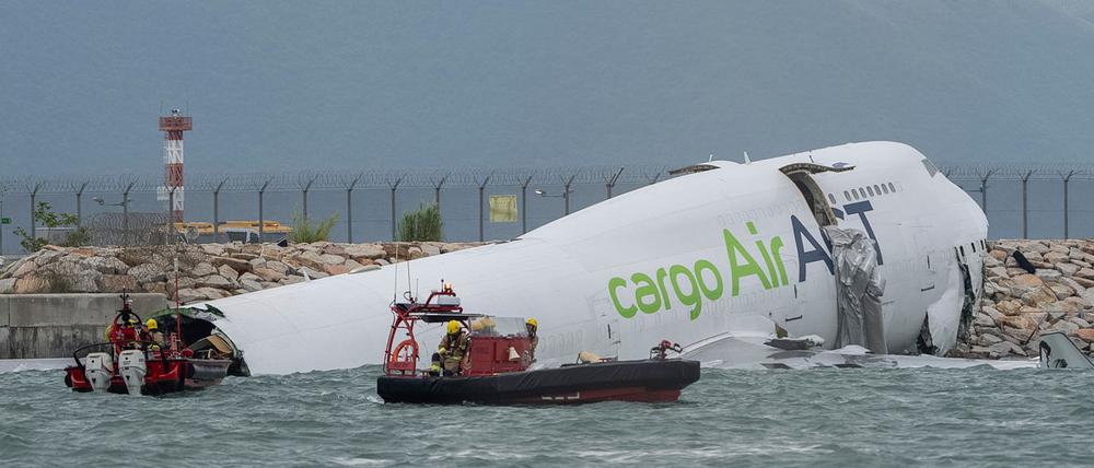 Rettungskräfte auf Booten schwimmen um das Frachtflugzeug, das auf dem Flughafen in Hongkong von der Landebahn abgekommen ist.