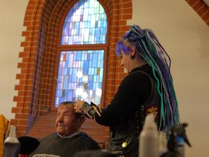 „Barber Angel“ Anni schneidet ihrem Gast Renate kostenlos die Haare in der Pauluskirche.