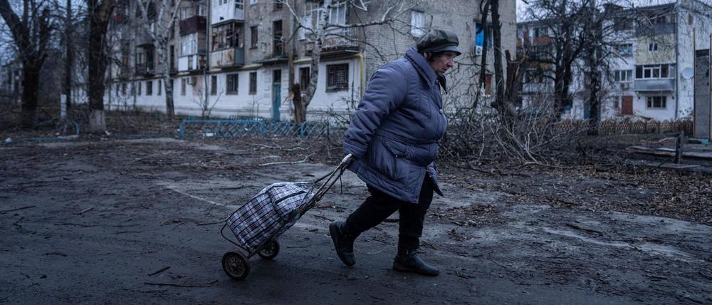 Ukraine, Kupjansk: Eine Einheimische geht zur Verteilungsstelle für humanitäre Hilfe vor einem Haus, das nach ukrainischen Angaben durch russischen Beschuss beschädigt wurde.