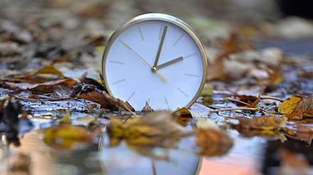 Eine Uhr spiegelt sich im blätterbedeckten Wasser. Mit Beginn der Winterzeit werden in Deutschland und den meisten anderen Ländern Europas am Sonntagmorgen (26. Oktober) die Uhren von 3.00 Uhr auf 2.00 Uhr zurückgestellt. Bis zum 29. März 2026 gilt dann wieder die mitteleuropäische Zeit (MEZ), auch Winterzeit genannt.
