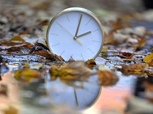 Eine Uhr spiegelt sich im blätterbedeckten Wasser. Mit Beginn der Winterzeit werden in Deutschland und den meisten anderen Ländern Europas am Sonntagmorgen (26. Oktober) die Uhren von 3.00 Uhr auf 2.00 Uhr zurückgestellt. Bis zum 29. März 2026 gilt dann wieder die mitteleuropäische Zeit (MEZ), auch Winterzeit genannt. 