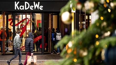 Menschen gehen am verkaufsoffenen Sonntag hinter einem Weihnachtsbaum am Kaufhaus des Westens (KaDeWe) vorbei. +++ dpa-Bildfunk +++
