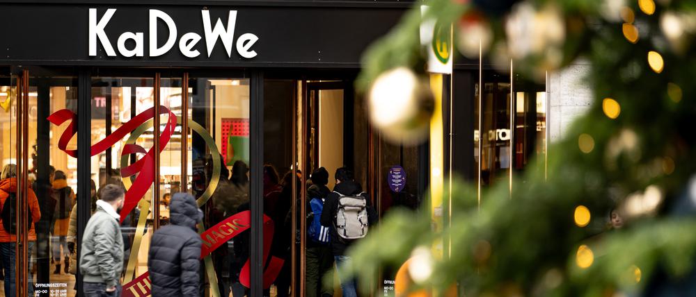 Menschen gehen am verkaufsoffenen Sonntag hinter einem Weihnachtsbaum am Kaufhaus des Westens (KaDeWe) vorbei. +++ dpa-Bildfunk +++