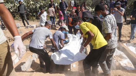 Männer begraben die Überreste nicht identifizierter Palästinenser auf einem Friedhof in Deir al-Balah im zentralen Gazastreifen, nachdem ihre Leichen im Rahmen eines von den USA vermittelten Waffenstillstandsabkommens am 22. Oktober 2025 von Israel zurückgegeben worden waren.