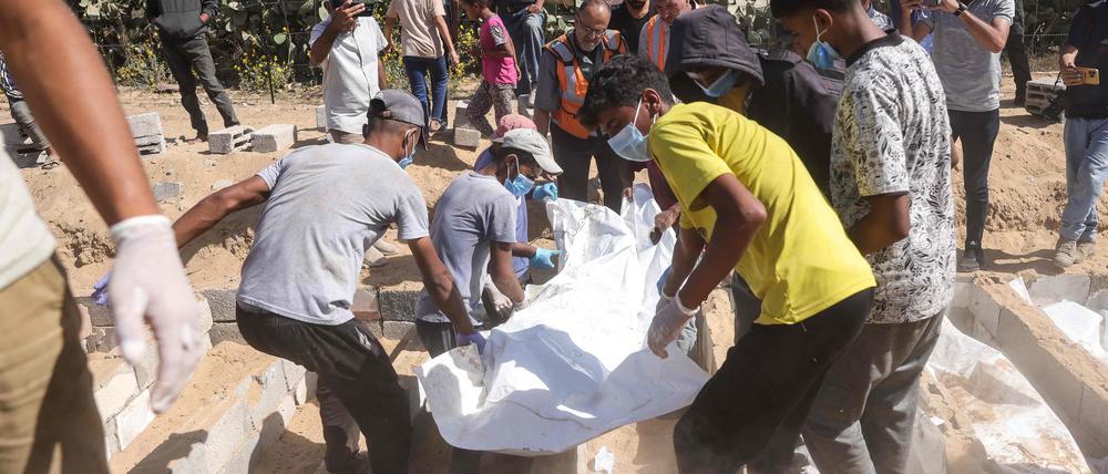Männer begraben die Überreste nicht identifizierter Palästinenser auf einem Friedhof in Deir al-Balah im zentralen Gazastreifen, nachdem ihre Leichen im Rahmen eines von den USA vermittelten Waffenstillstandsabkommens am 22. Oktober 2025 von Israel zurückgegeben worden waren.