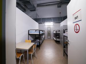 Blick in einen Raum mit Betten, Schränken und einem Tisch im sogenannten Dublin-Zentrum in Hamburg-Rahlstedt.