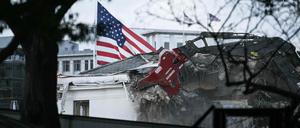 Ein Abrissbagger gräbt sich in die Fassade des Ostflügels am Weißen Haus.