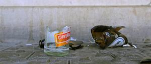 Die Scherben von zerbrochenen Glasflaschen liegen auf einem Fußweg vor einer Treppe.