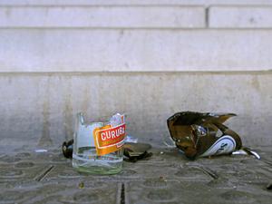 Die Scherben von zerbrochenen Glasflaschen liegen auf einem Fußweg vor einer Treppe. 