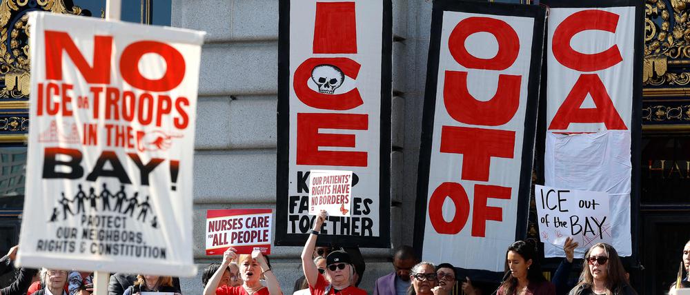 Demonstranten halten während einer Anti-ICE-Demonstration vor dem Rathaus von San Francisco Schilder hoch.
