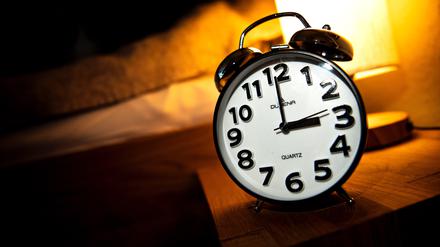 Eine Uhr steht neben einem Bett. Am letzten Sonntag im Oktober beginnt die sogenannte Winterzeit, dabei werden die Uhren zurückgestellt.